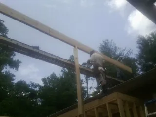 Carpenter setting a ridge beam over a new addition frame — Ice Dam Removal by Roofing Brothers in Mad River