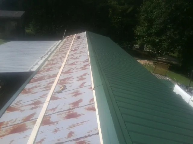 Old rusted panels beside newly installed green metal roofing — Wind Damage Roof Repair by Roofing Brothers in Mad River
