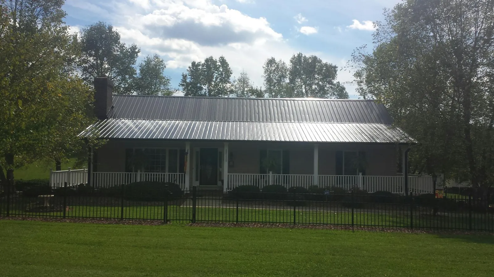 Gray metal roof on a brick ranch with a full width front porch — Gutter Guard Installation work by our crew in Mad River