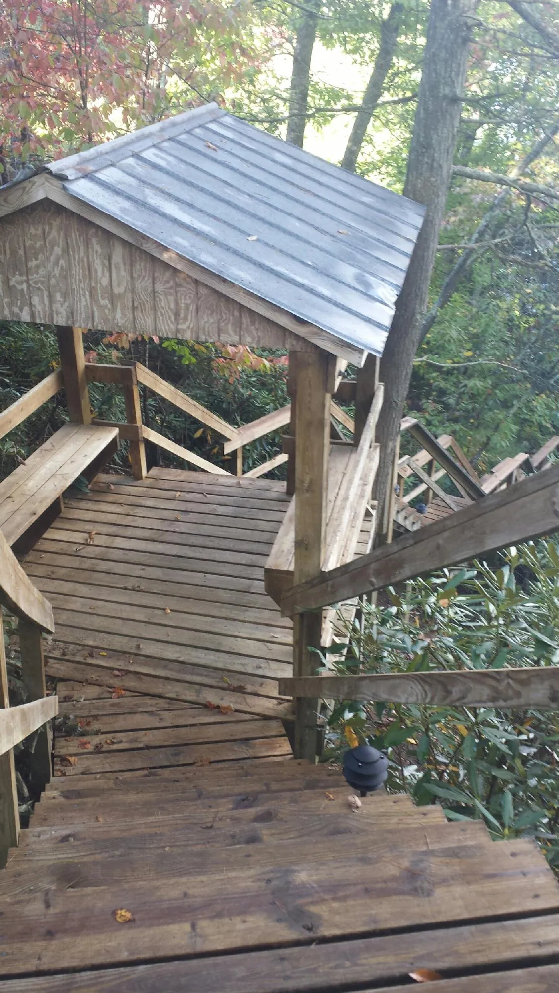 Metal roofed shelter over wooden steps on a wooded walkway — Skylight Repair & Installation work by our crew in Mad River