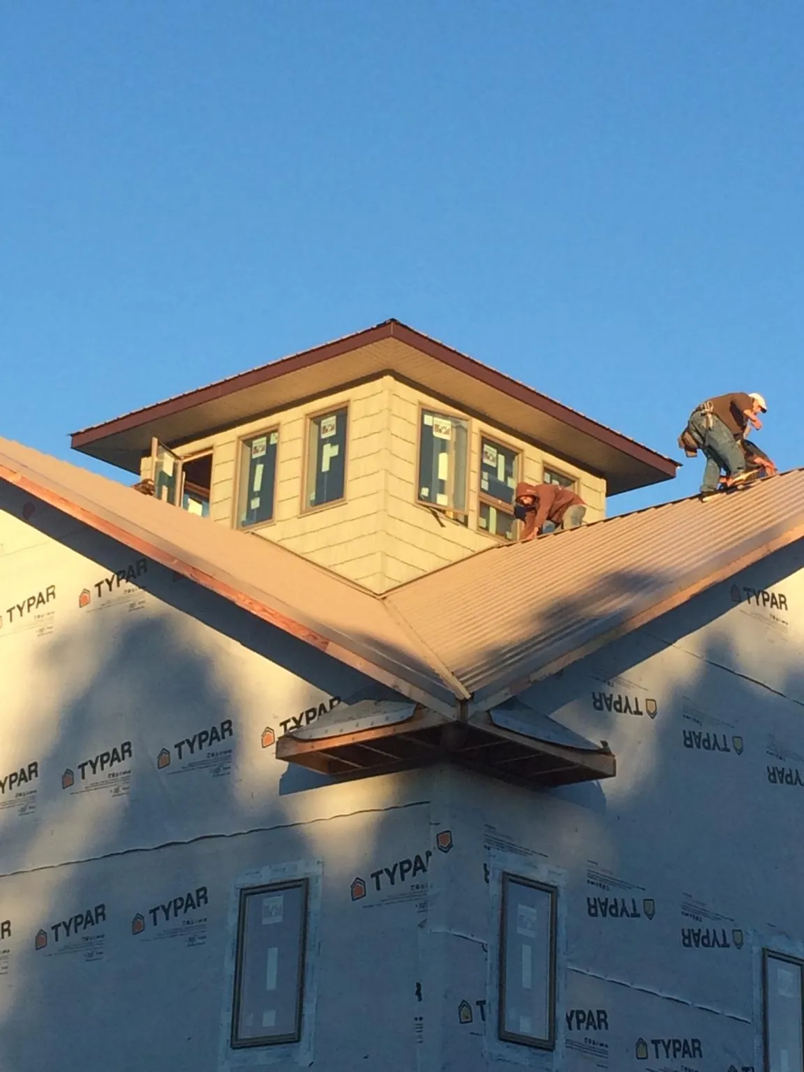 Roofers working around a rooftop cupola on a new metal roof at sunset — Roof Waterproofing in Mad River by Roofing Brothers